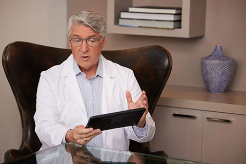 Telehealth WhiteMaleDoctorwithGlasses TalkingonTablet web flip